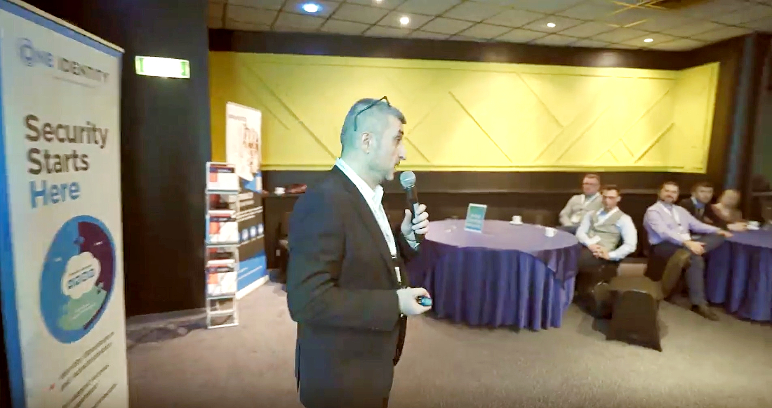 a man is talking into a mic and presenting to a room of people.