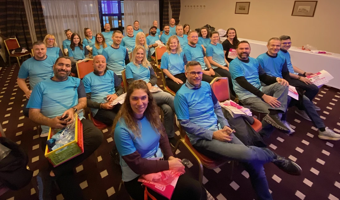 Un grand groupe de personnes portant des t-shirts bleus rassemblées dans une pièce