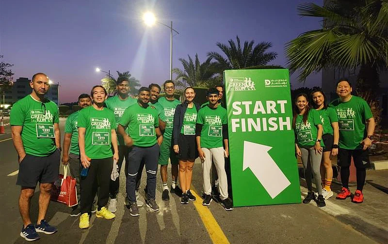 13 personnes en t-shirts verts sont réunies pour une photo de groupe après une course.