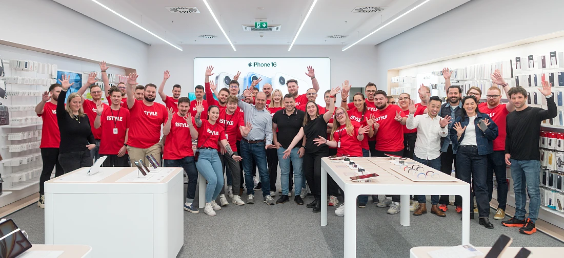 Photo de groupe montrant l'équipe iSTYLE de Brno en t-shirts rouges, saluant et souriant.