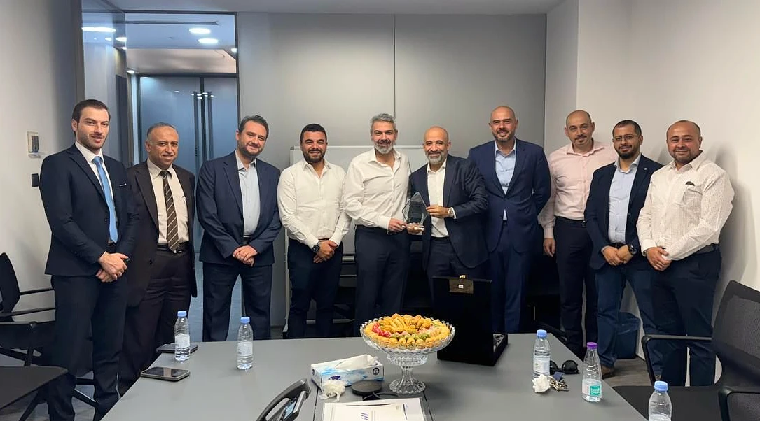 Ten men are seen in a boardroom with one man in the center holding a glass trophy