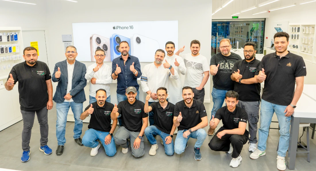 fifteen men seen in a smiling group photograph taken in a hi-tech store