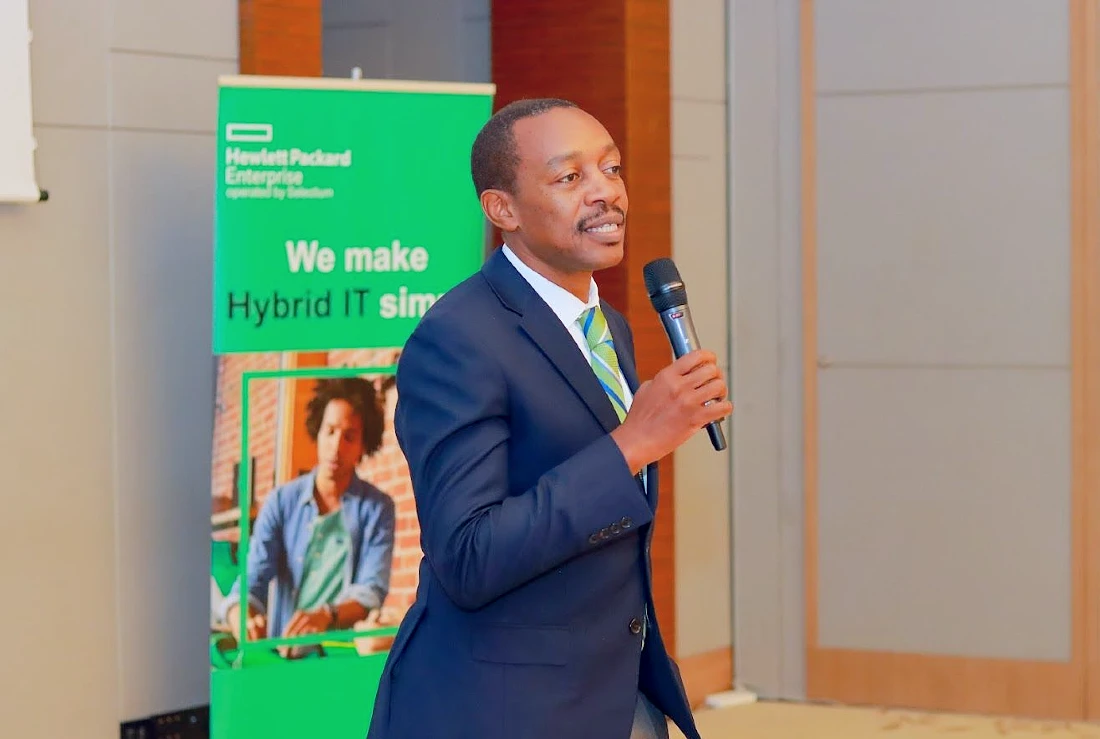 a man in a suit and tie speaks into a mic and presents at a hi-tech event.