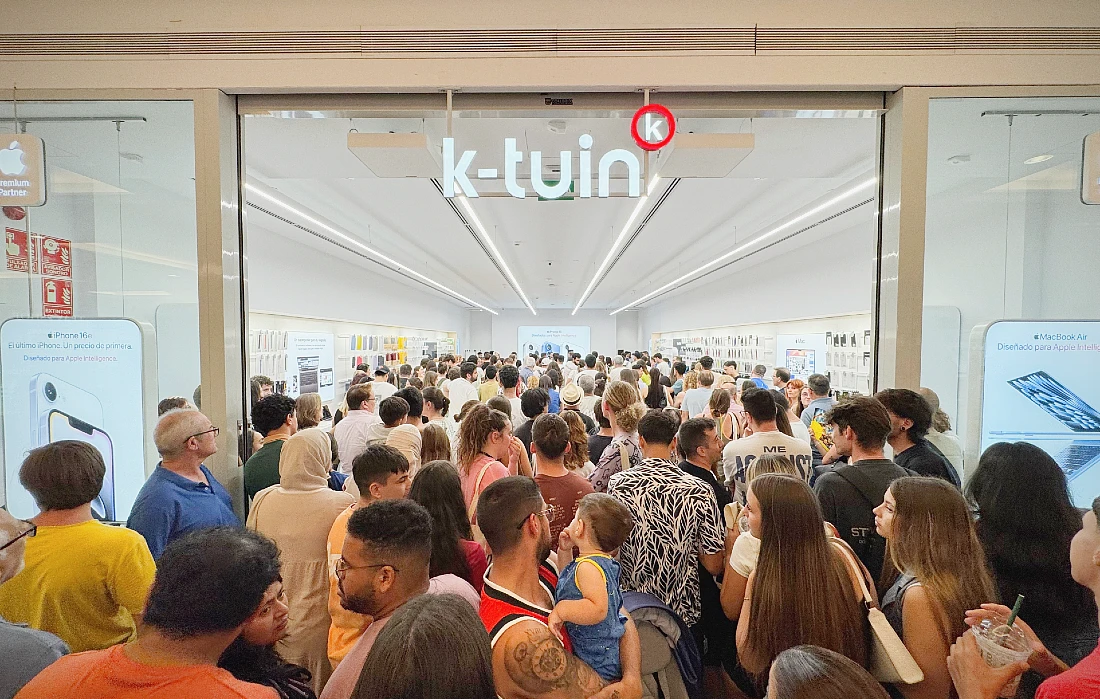 a really large crowd of people are seen outside and inside a hi tech store at an opening event