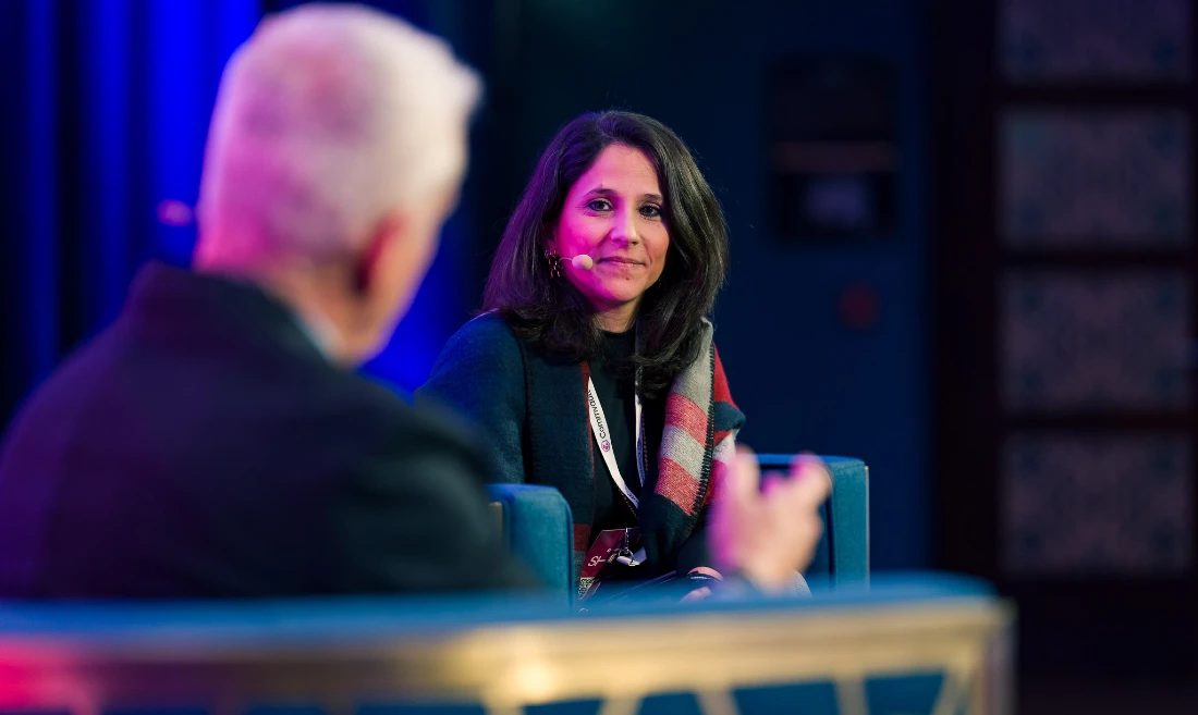 a woman is seen speaking to a man during a discussion on stage at a hi tech event