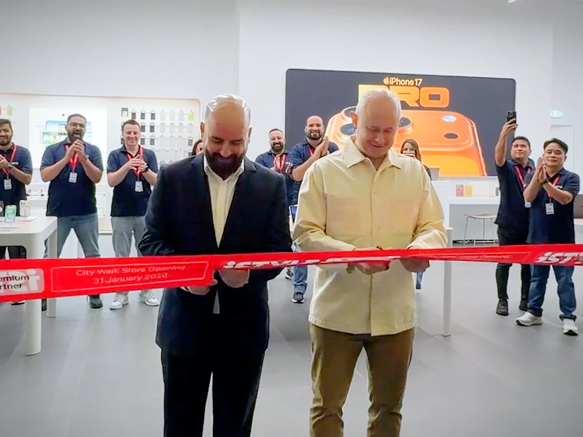 two men are seen about to cut a red ribbon to open a new store