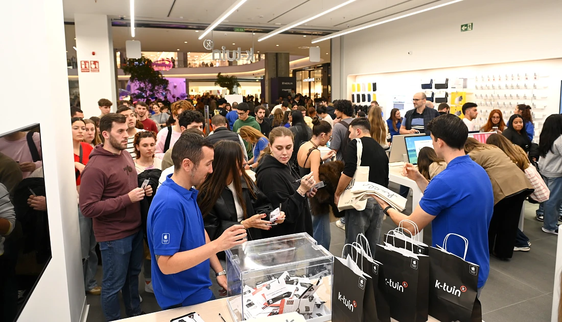 Scène animée dans un magasin high-tech : des clients arrivent pour utiliser leurs bons de réduction.