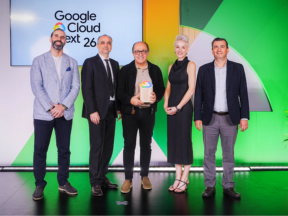 Five people on stage at a hi tech event accept an award with a colourful background behind them.