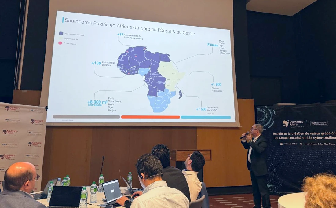 A man is seen presenting to an audience whilst looking up at a screen showing a map of Africa