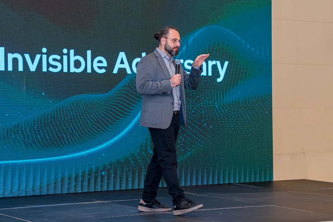 A man talks into a mic onstage at a cyber security event