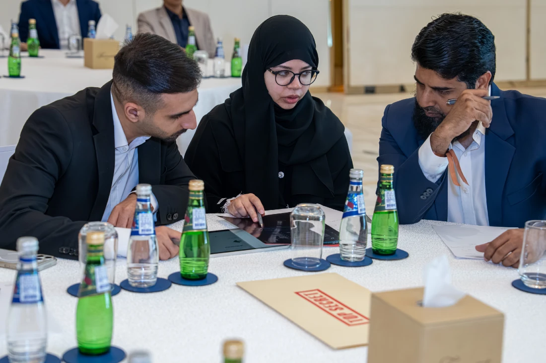 three people talk together as one of them makes notes at a cyber security exercise